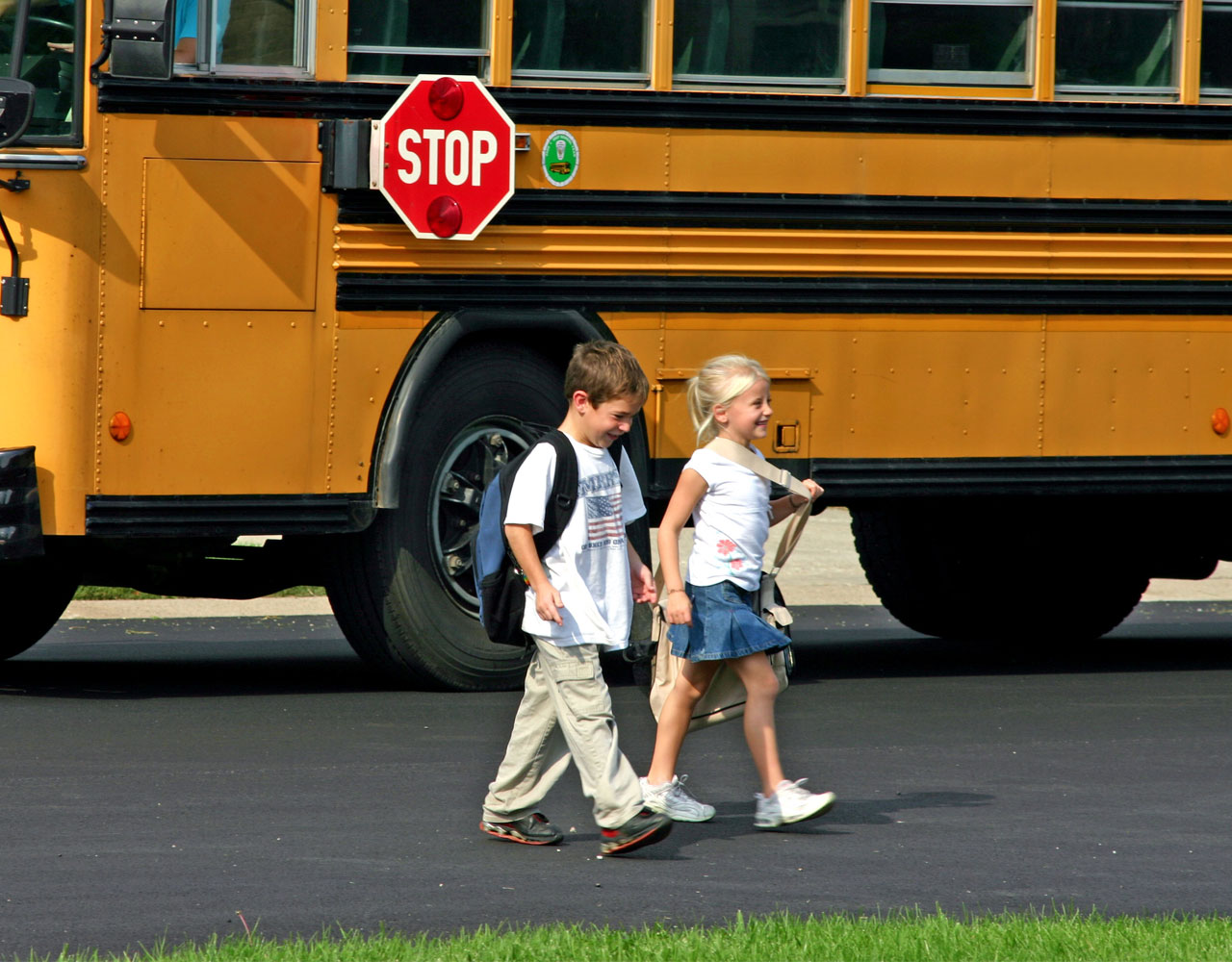 School kids walking safely next to school bus